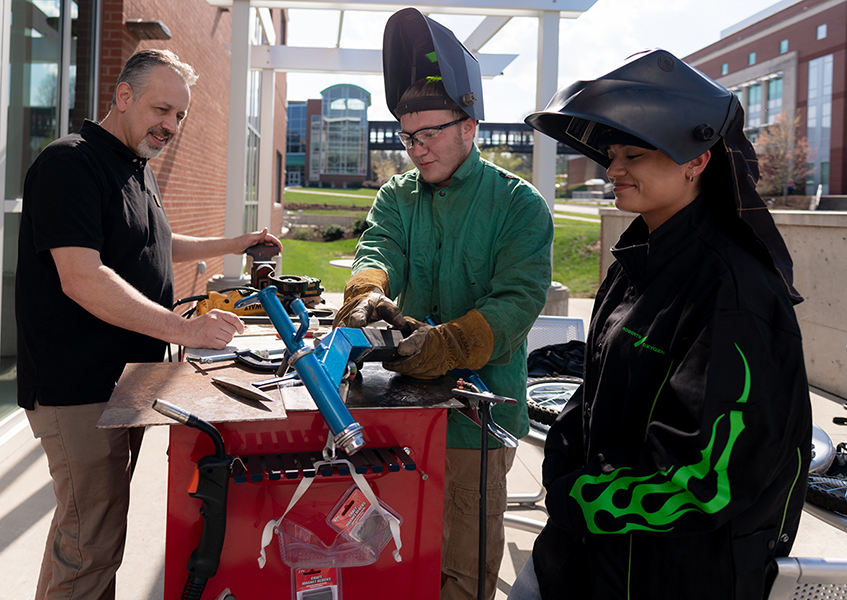 Male welding teacher and male and female students